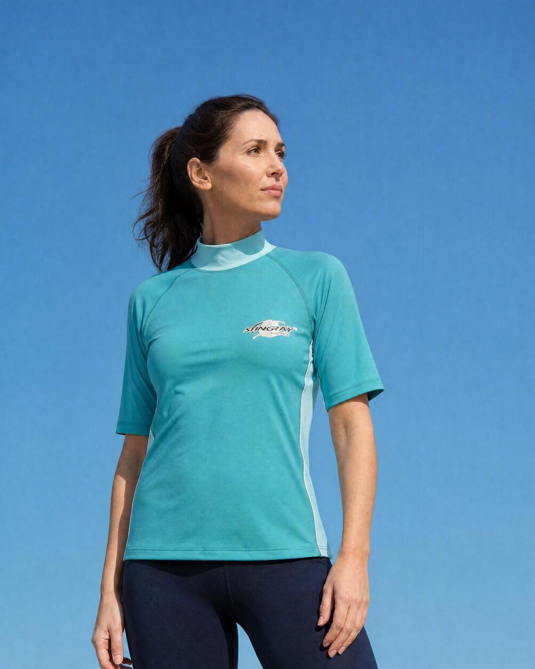 Woman wearing a women's aqua teal short sleeve UV swim shirt UPF 50+ at the beach