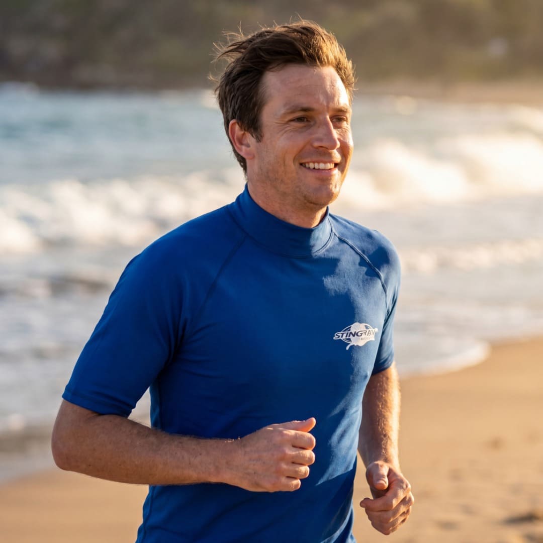 Man wearing ocean blue UV rash vest UPF 50+ on beach