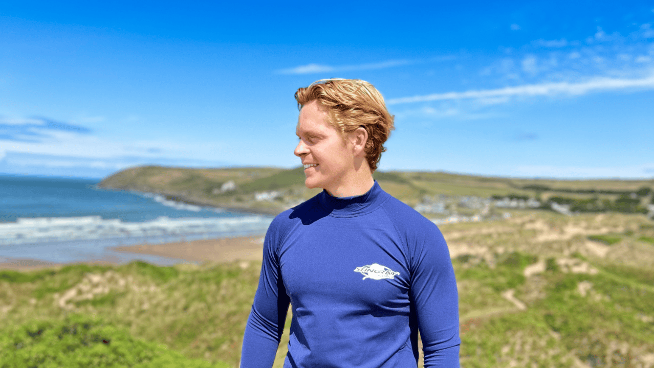 Man wearing a blue upf rash shirt on a beach