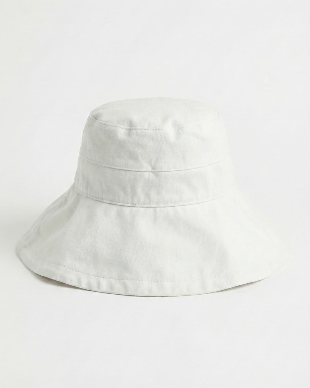 Wide brim white UPF 50+ sun hat in a grey studio setting