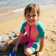 Review pic: girl wearing short sleeve UPF 50+ swimsuit sitting on the beach