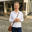 Review pic: woman wearing UV protection polo shirt with long sleeves whilst standing on the street with a coffee