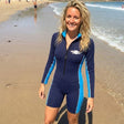 Review pic: woman wearing UV protection sunsuit with long sleeves, standing on the beach in Sandbanks UK