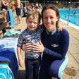 Review pic: woman wearing full-body UV protection sunsuit next to a pool with her child