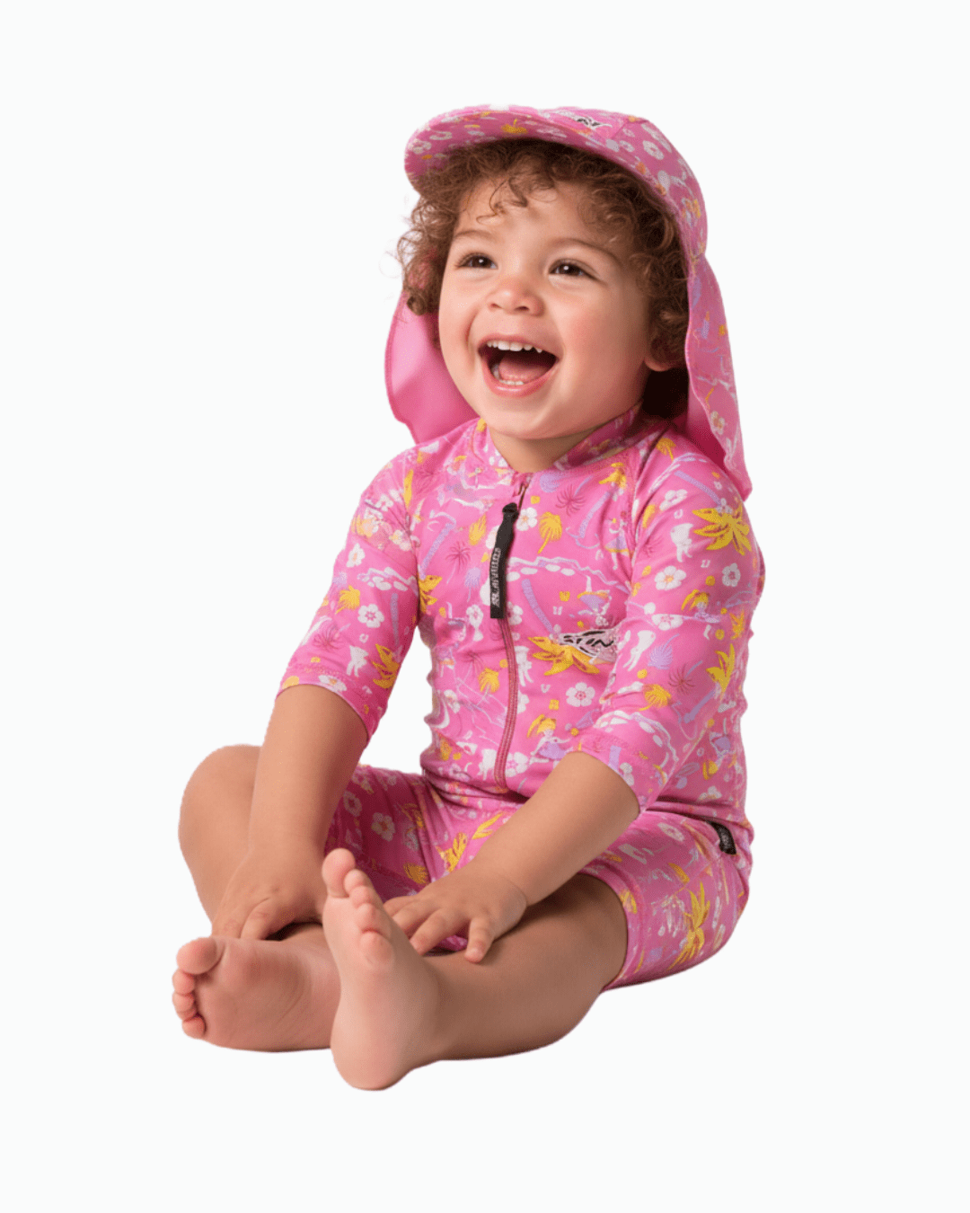 Toddler wearing a pink floral UV swimsuit and cap on a white background