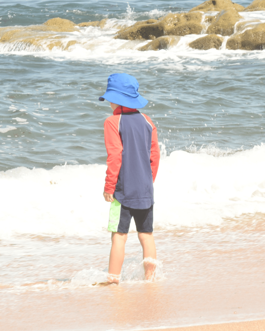 Child playing in the sea with a UV protection long sleeve rash shirt on