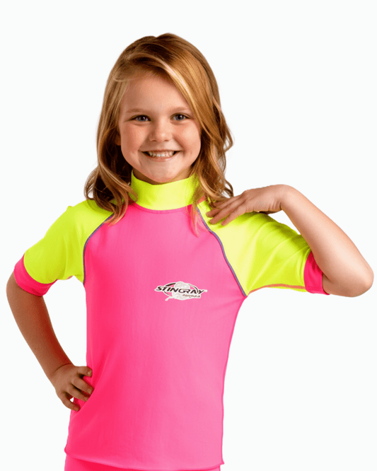 Young girl wearing a pink and yellow upf rash vest with a Stingray logo on a white background