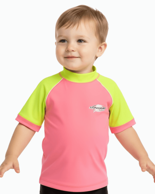 Toddler wearing a pink and yellow UPF swim shirt with a Stingray logo on a white background