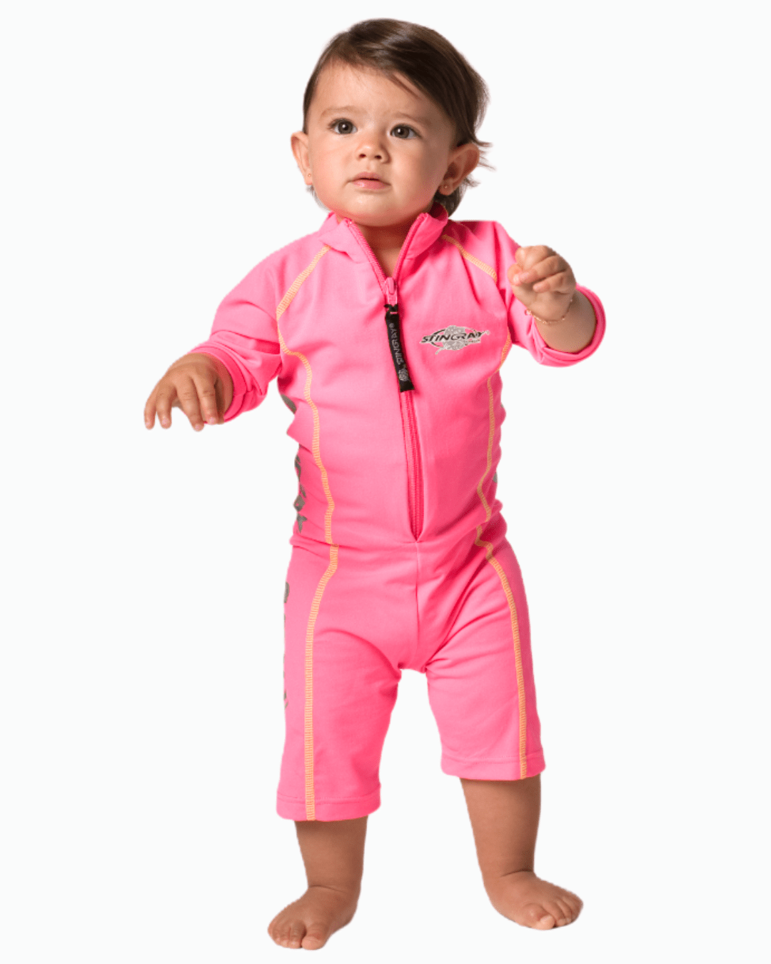 Baby wearing a pink sun suit with a zipper on a white background