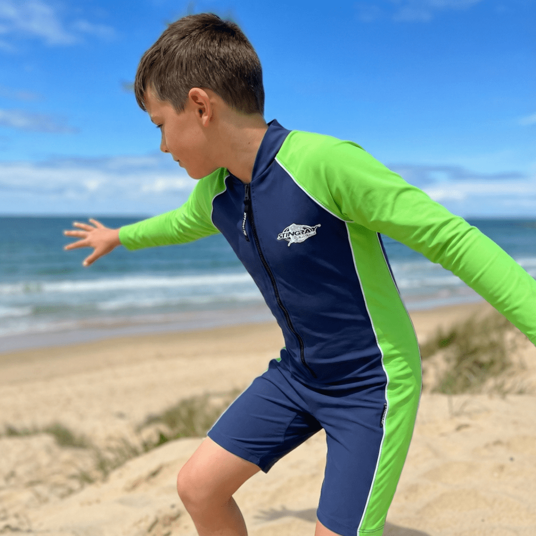 Child wearing a blue and green UV swimsuit on a beach