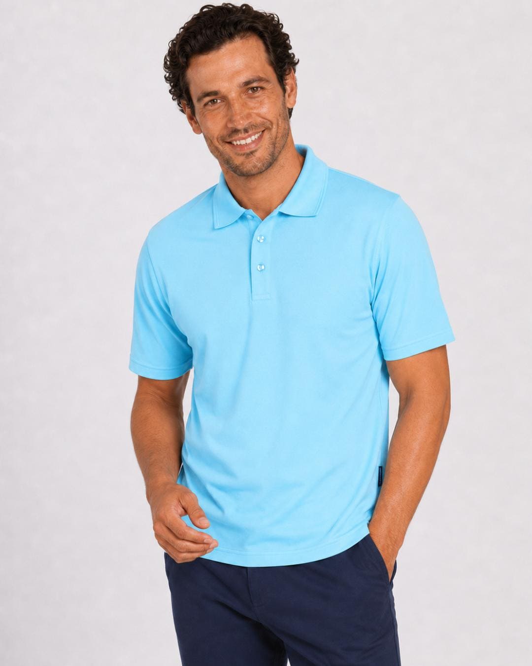 Man wearing a short-sleeve ice blue UV polo shirt and dark pants on a light grey background
