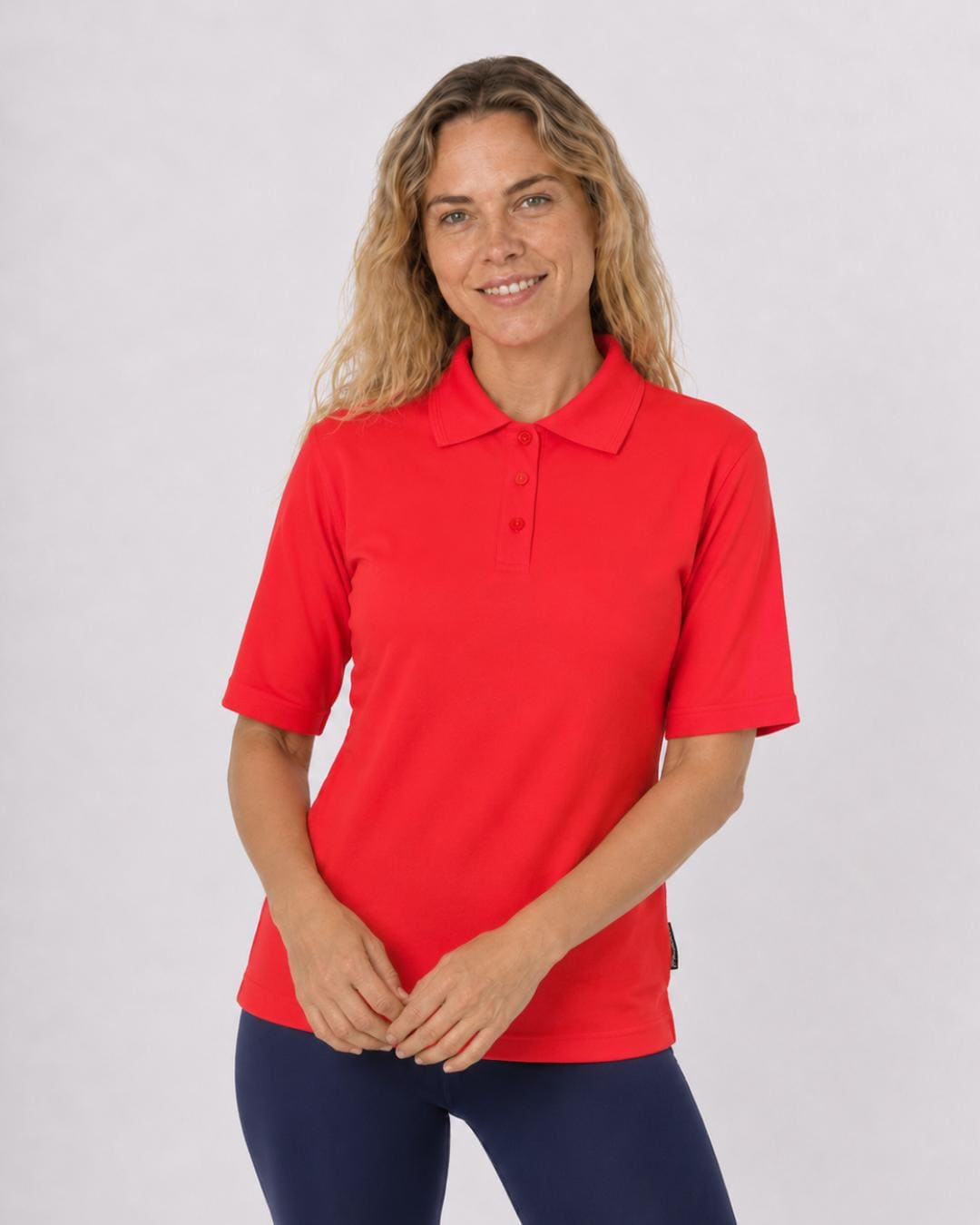 Woman wearing a red short sleeve UV polo shirt and navy leggings on a white background