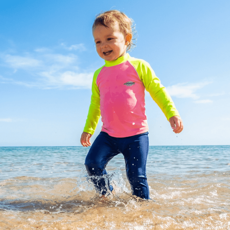 2 year old toddler wearing a bright UV swim shirt in the sea