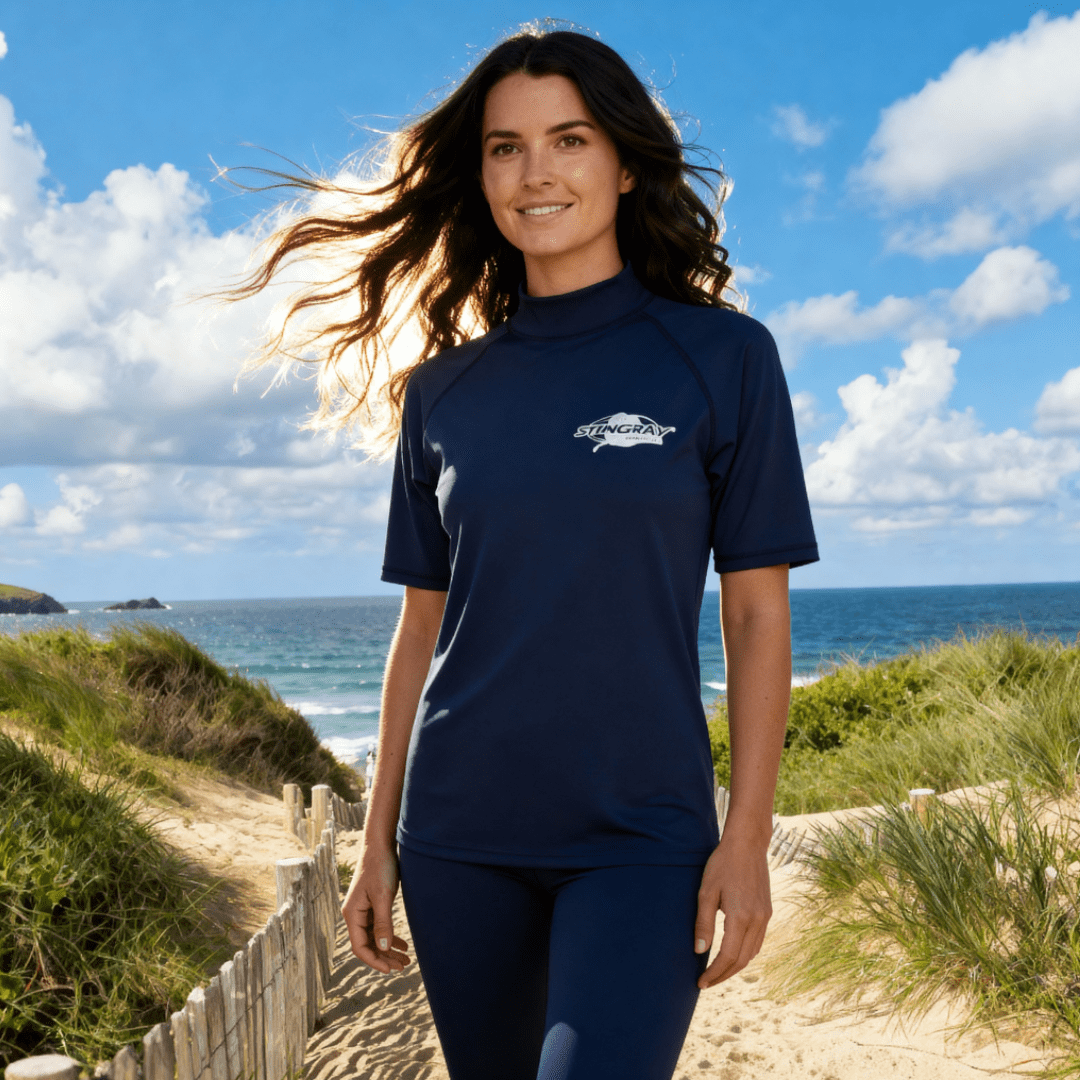 Woman wearing a navy blue uv swim top with a Stingray logo on a beach