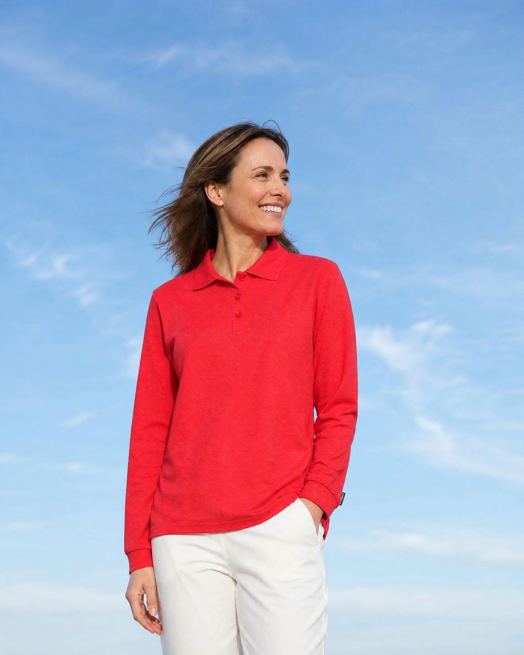 Woman wearing a red long-sleeve UV polo shirt UPF 50+ against a blue sky