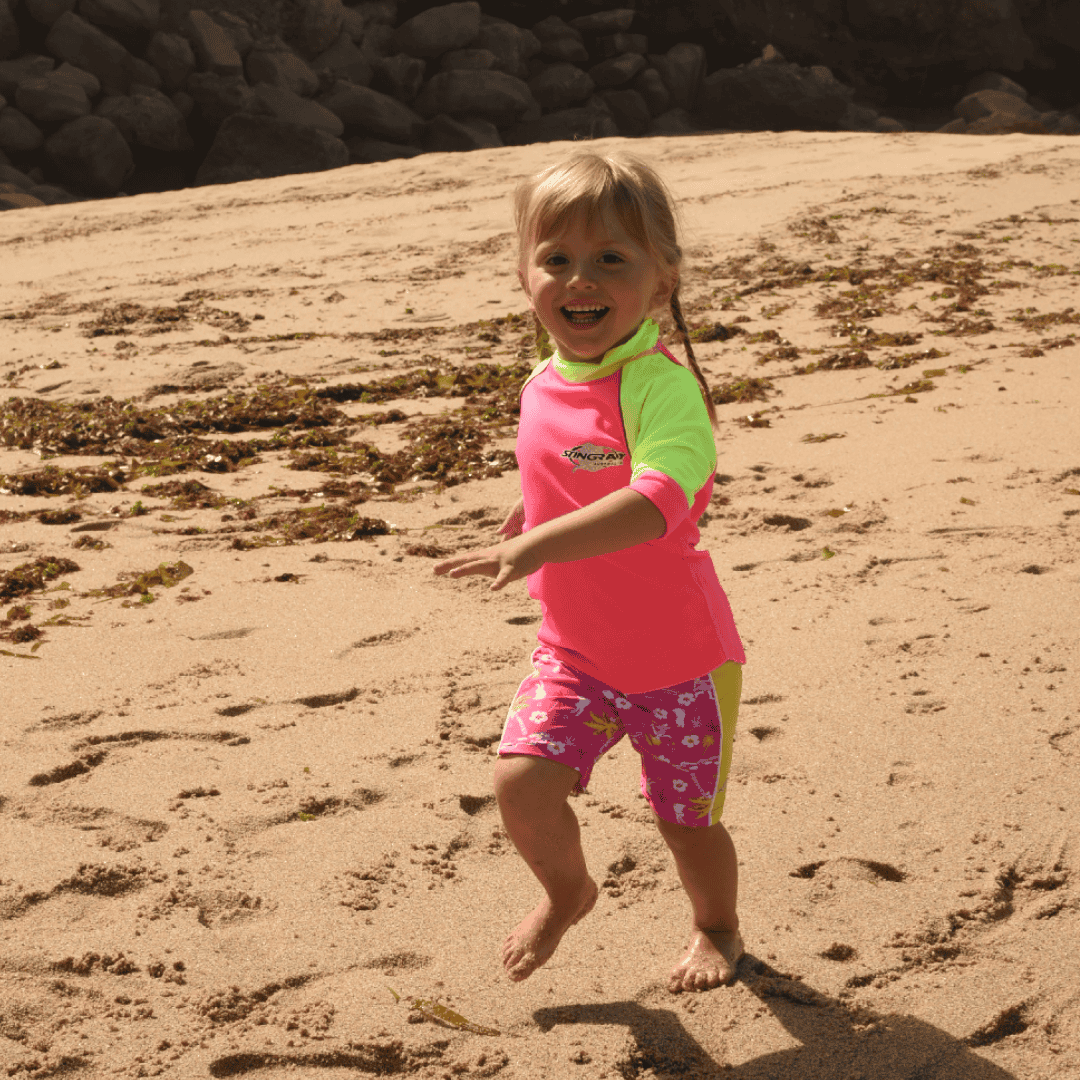 Child running on beach wearing UPF swim shorts in hawaii style print